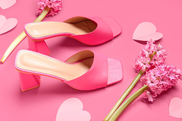 Female shoes with hyacinth flowers and paper hearts on pink background