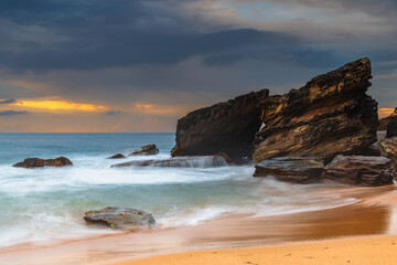 Sunrise at the seaside with rocks and beautiful diffused light by the rain clouds