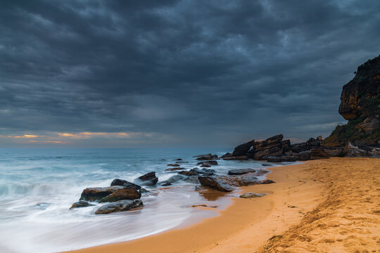 Sunrise at the seaside with rocks and beautiful diffused light by the rain clouds