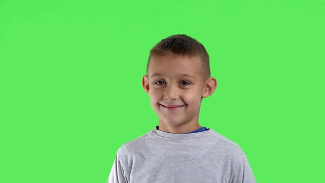 Portrait of a smiling boy with a green screen in the background

