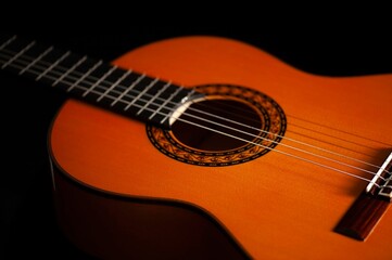 Classical Spanish flamenco guitar close up, dramatically lit isolated on black background with copy space.