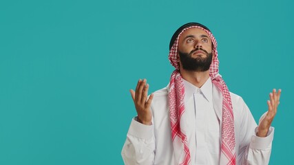 On camera, arab person seeks to Allah trusting in sacred practices over blue background. Middle...