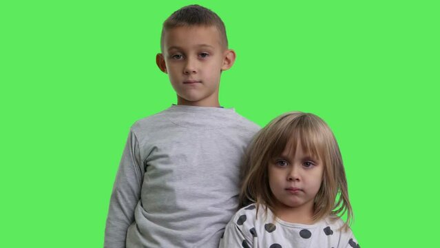 Portrait of a smiling a boy and a girl with green screen in background