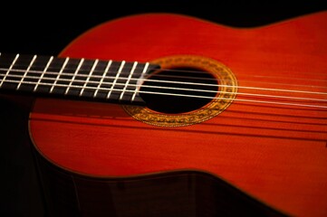 Fototapeta premium Classical Spanish flamenco guitar close up, dramatically lit isolated on black background with copy space.