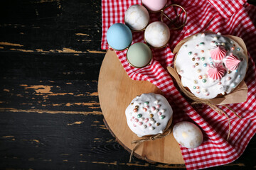 Board with sweet Easter cakes and eggs on black wooden table