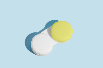 A white container with a green lid for contact lenses on a blue isolated background. Ophthalmological diseases, vision improvement concept