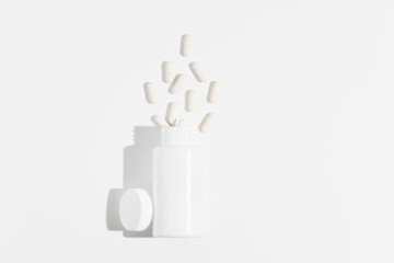 White mockup jar with scattered natural pills on white isolated background. Concept of pharmacy, dietary supplements, health care and medicine. images for your design