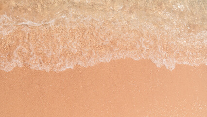 Soft wave edges hitting sandy beach with clear water, in natural daylight.