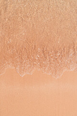 Gentle waves lapping over smooth sand, creating delicate textures.