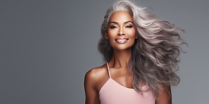 Silver haired woman with dark toned skin on gray background 