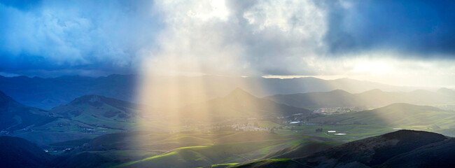 Panorama of rays of light, sunbeams, shining through clouds in valley