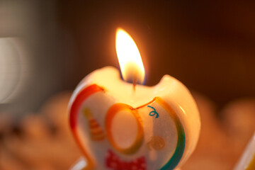 A close-up image capturing the gentle glow of a lit number eight birthday candle, adorned with...