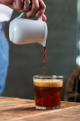 Pouring Freshly Brewed Coffee into Glass on Wooden Counter, Steam Rising
