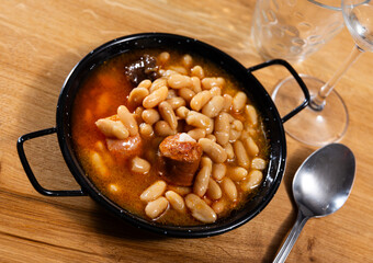 Asturian fabada soup with white beans and blood sausage served in bowl