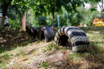 A tire is sitting in the grass next to a row of tires