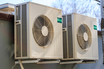 Two air conditioners are mounted on a wall
