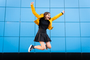 Happy girl jumping for joy during yellow day, the happiest day of the year.