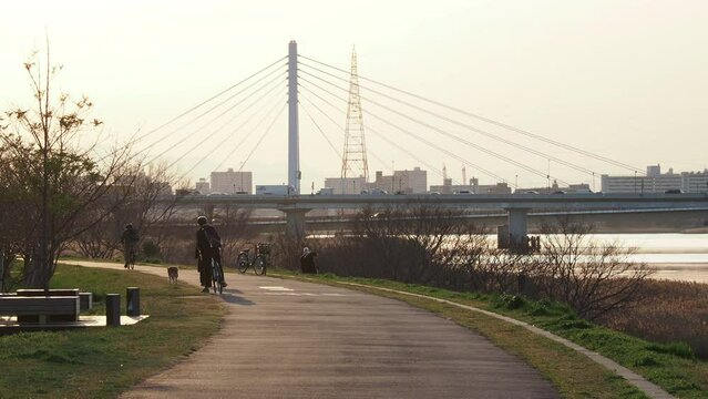 夕方の東京都の多摩川の大師橋の様子と沿岸で散歩する人々の姿