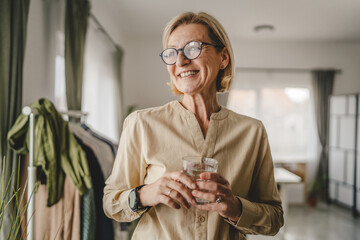Portrait of one adult mature woman hold glass of water at home