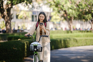 Beautiful woman taking a bike stroll in the park, business woman holding smartphone using bike rental, business woman holding smartphone using bike rental digital phone.