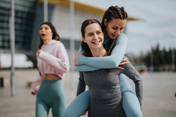 Two cheerful women embracing in workout attire, celebrating success with a joyful friend in the...