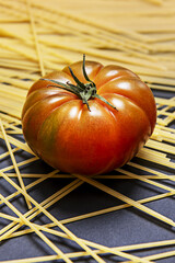 A few glossy raf tomatoes on spaghetti and a smooth black surface - obrazy, fototapety, plakaty