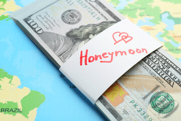Stack of money with word Honeymoon on world map, closeup