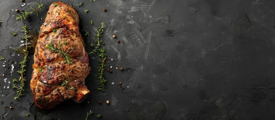 Foto op Plexiglas Whole leg of lamb mutton roasted in the oven with thyme on a black surface, seen from above with space for text. © Vusal