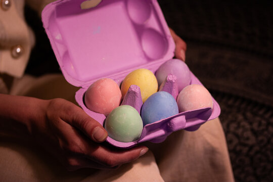 Collection of beautifully painted Easter eggs nestled in a violet box in woman's hands. Vibrant colors festive greeting card. Woman open egg box.