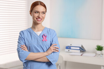 Mammologist with pink ribbon in hospital, space for text. Breast cancer awareness