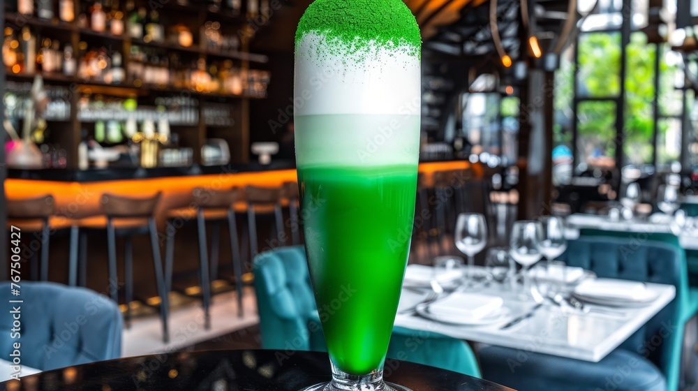 Poster a green and white drink sitting on top of a table in front of a bar filled with bottles of wine.