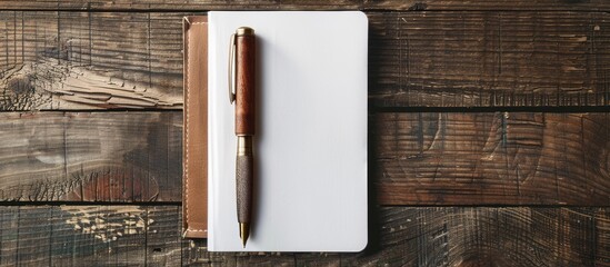 Mock-up of a pen on a wooden table with a white diary cover. - Powered by Adobe