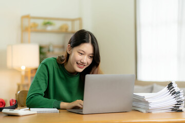 Ambitious Asian girl working from home Looking at laptop screen and smiling, checking mail or doing...