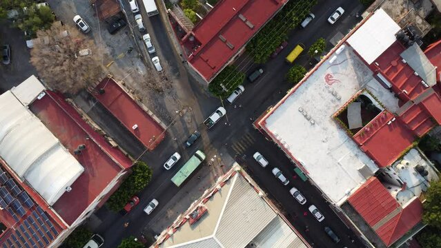 Vista a&eacute;rea cenital de una intersecci&oacute;n urbana con tr&aacute;fico y edificios de techos rojos