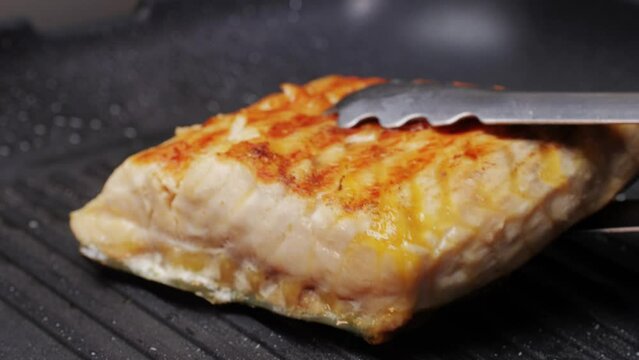 Cooking fillet sturgeon beluga white fat fish on grill or frying pan with oil close-up. Roast healthy food concept. Fry sturgeon, hake, cod fish steak pieces fillet. Healthy diet