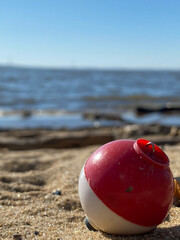 red and white fishing bobber lure on the sand on the beach