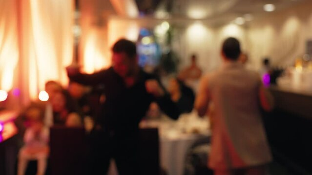 Blurred image depicts a man and a woman dancing at a lively party event