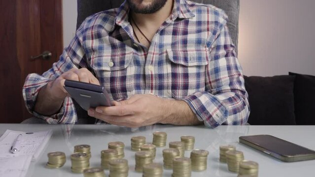 Close up of man's hands doing accounts and accounting with his calculator counting gold coins prepare his taxes