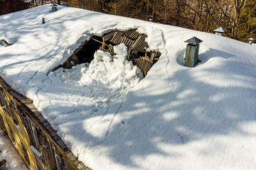 Broken roof under the weight of fallen snow on an old building from a drone - obrazy, fototapety, plakaty