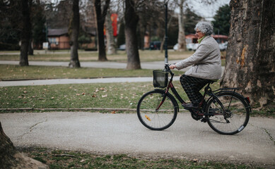 A mature woman retiree riding a bicycle through a scenic park, showcasing an active lifestyle.