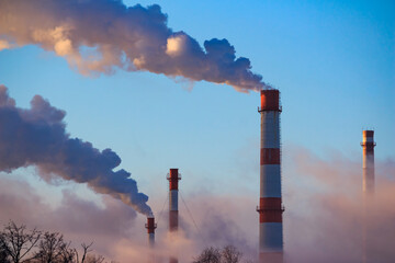 Smoking chimneys of boiler houses against a background of blue sky, industrial landscape