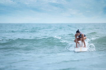 Asian surfing woman riding the waves on sunny day, outdoor activities, water sports activities concept