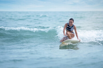 Asian surfing woman riding the waves on sunny day, outdoor activities, water sports activities concept