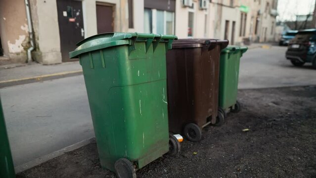 Row of waste containers on roadside, next to building and grass
