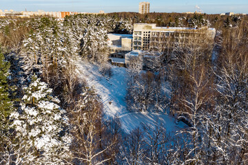 Top view of the snow-covered territory of the sanatorium surrounded by trees - obrazy, fototapety, plakaty