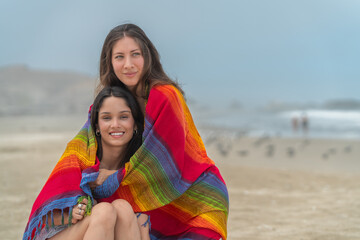 Lesbian couple wrapping in blanket after bath on the sea