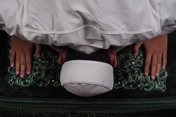 overhead shot of muslim man praying on prostration position on rug or carpet