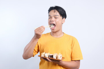 Man enjoying eating sushi with eyes closed over white background