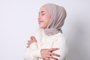 Portrait of Asian muslim woman embracing herself and smiling with pleasure, feeling self pride