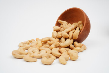 Tasty roasted cashew nuts spilling out of wooden bowl Isolated Background